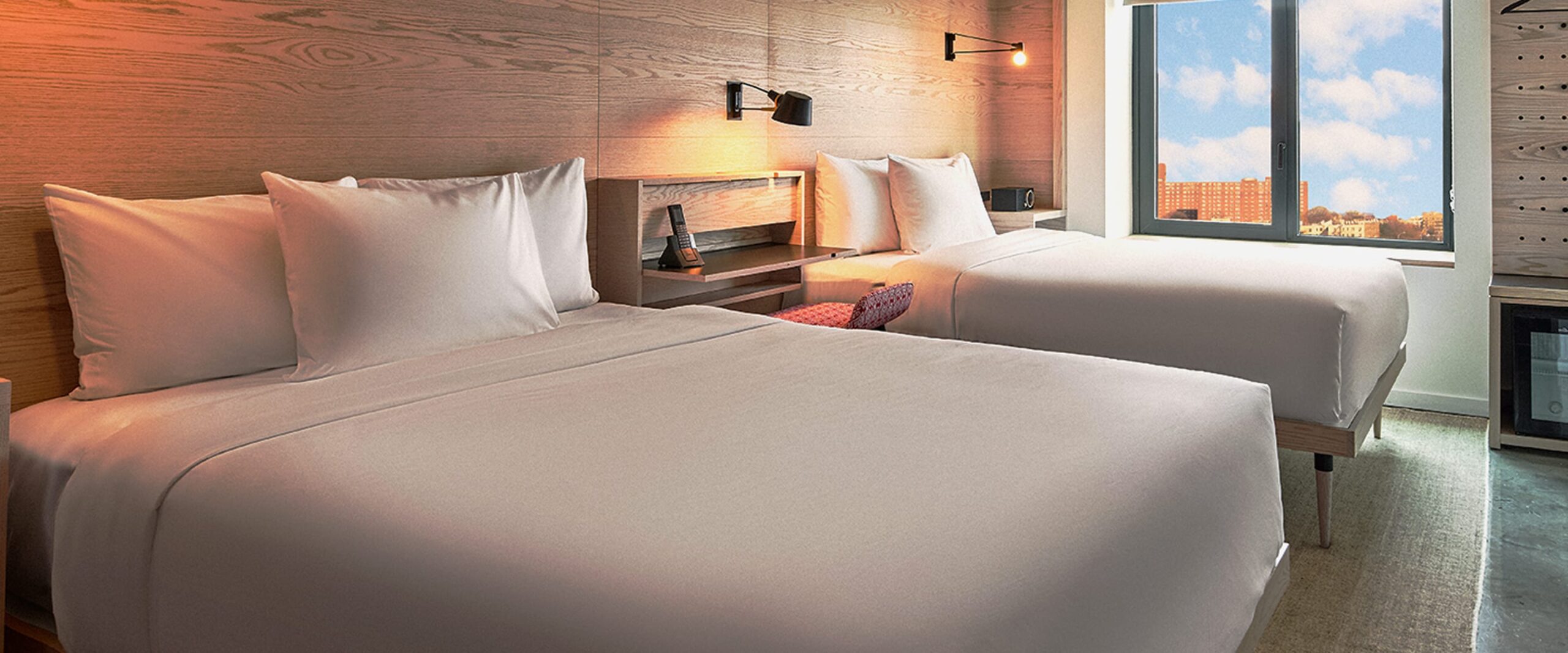 Two queen sized beds in hotel room overlooking NYC