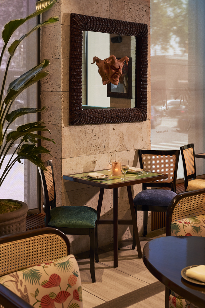 A cozy corner of a restaurant with a table, chairs, and a mirror on the wall.