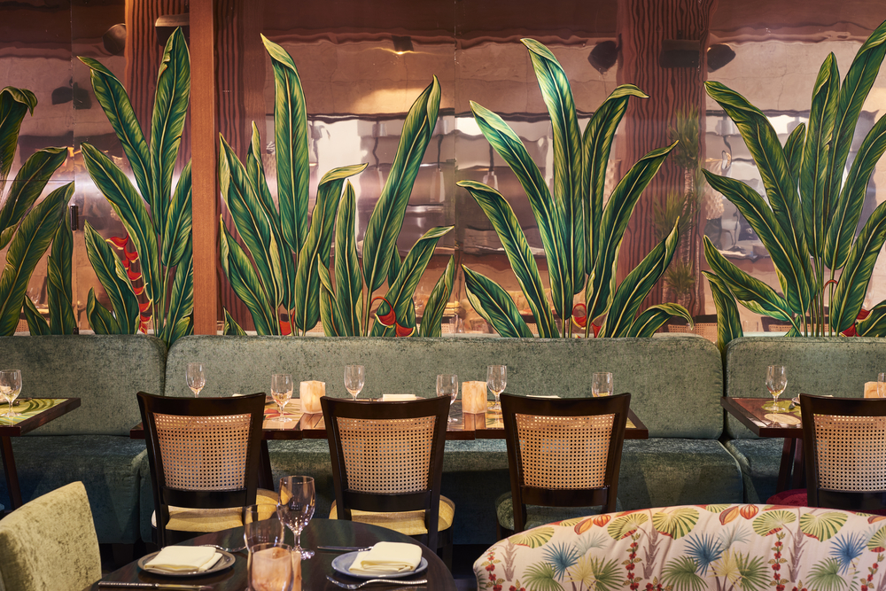 A restaurant dining area with tables, chairs, booths, and plants.