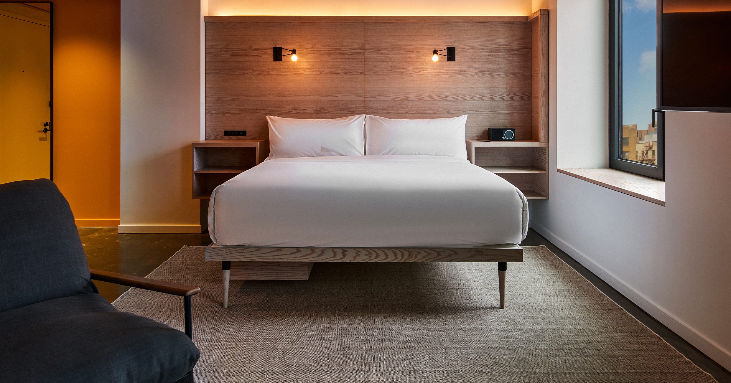 A hotel room with a large bed, chair, and window