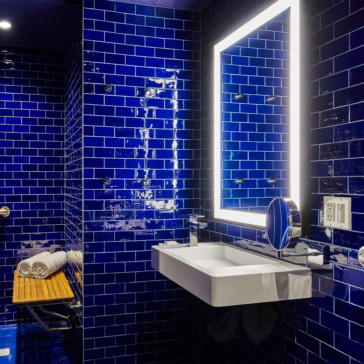 A bathroom with blue tile walls, a white sink, and a mirror.