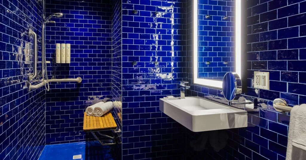 A bathroom with blue tiles, a white sink, and towels