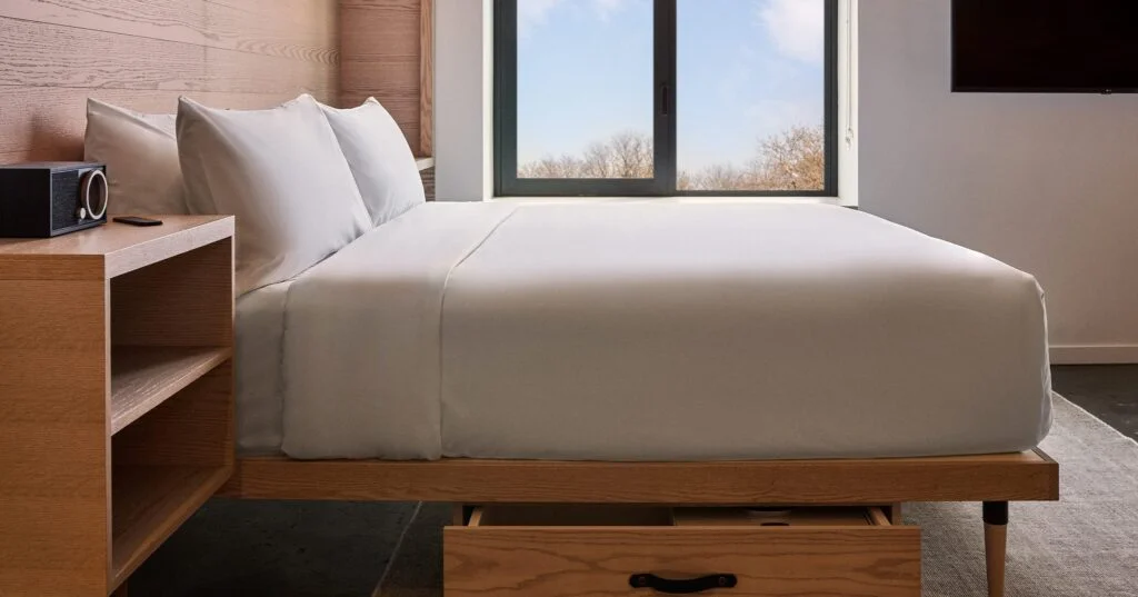 A hotel room with a bed, nightstand, and window