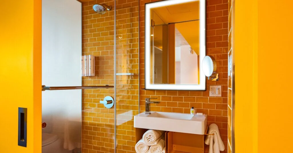 A bathroom with a tiled shower, sink, and mirror.