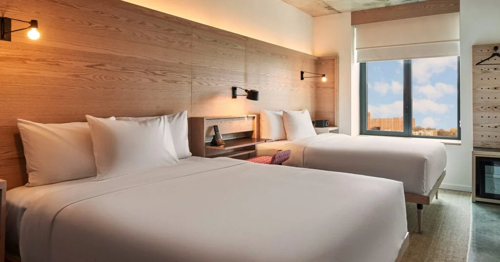 A hotel room with two beds, a window, and a closet