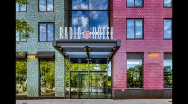 The exterior of the Radio Hotel with a colorful brick facade and a glass entrance.